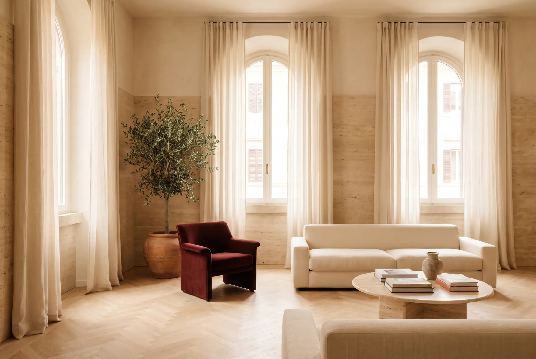 Soggiorno di un appartamento romano luminoso in stile travertino, con poltrona in velluto rosso oxblood