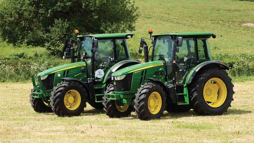 Two John Deere 5M series tractors in a green field