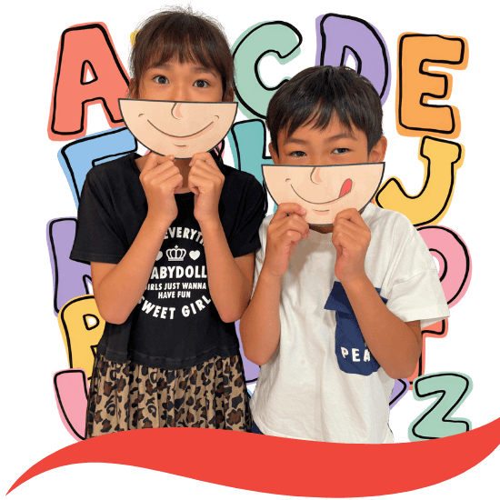 加須市の英語教室で笑顔の紙を顔に当てる子どもたち