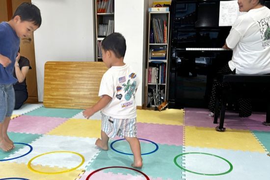 ピアノの音に合わせてフープを跳ぶリトミック教室の子どもたち
