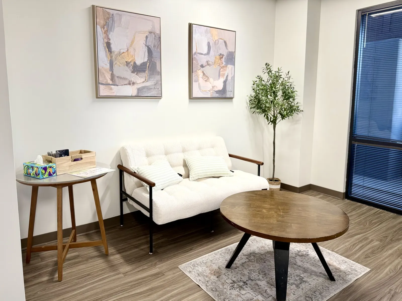 A bright therapy room at Arizona Counseling and Therapy Center with a sofa, artwork and a window