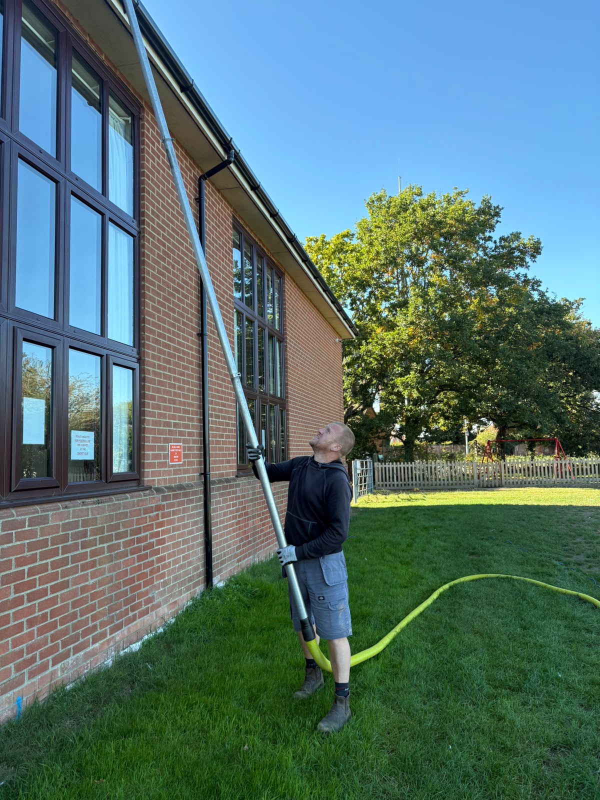 Nik clearing gutters on a commercial building with a high-reach vacuum