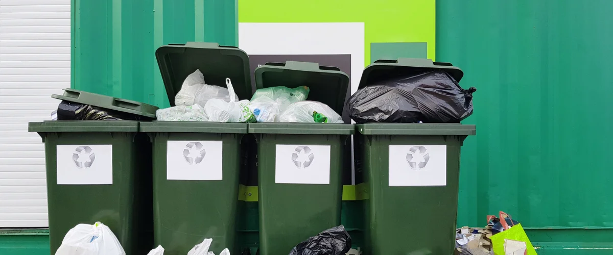 Public park trash can on grass beside a walking path