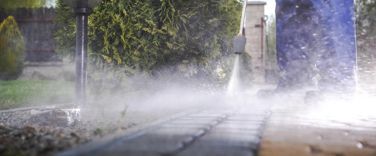 Steam pressure washer cleaning garden pathway pavers with mist visible