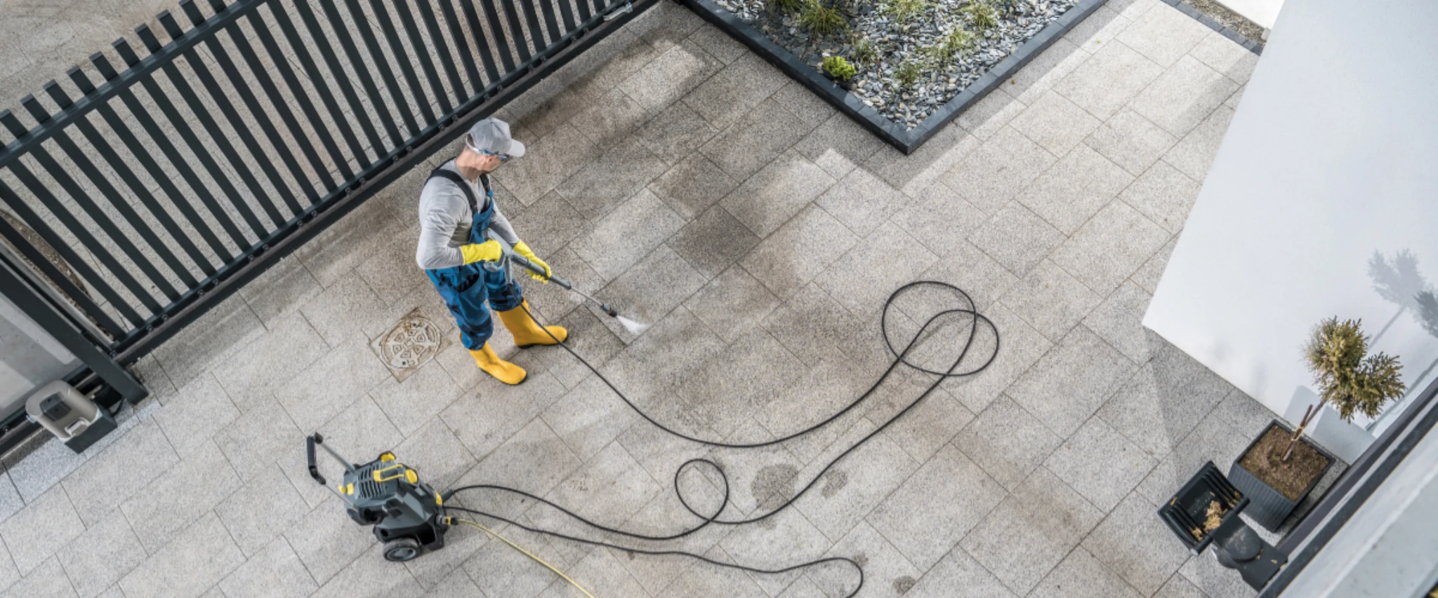Professional using pressure washer machine to clean residential patio from above  pressure-washing-brick-pavement.webp
