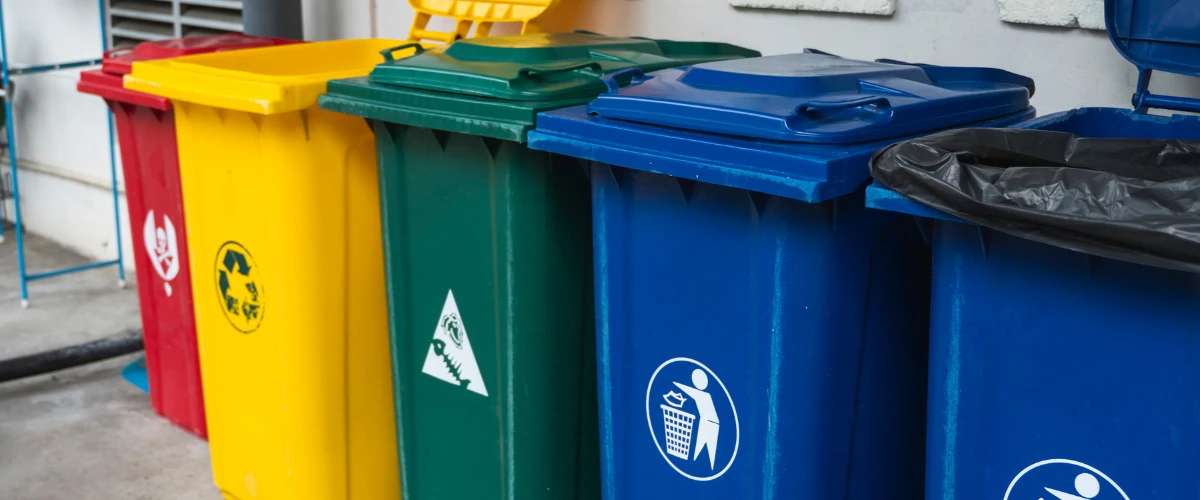 Row of colorful recycling wheelie bins for waste separation outdoors