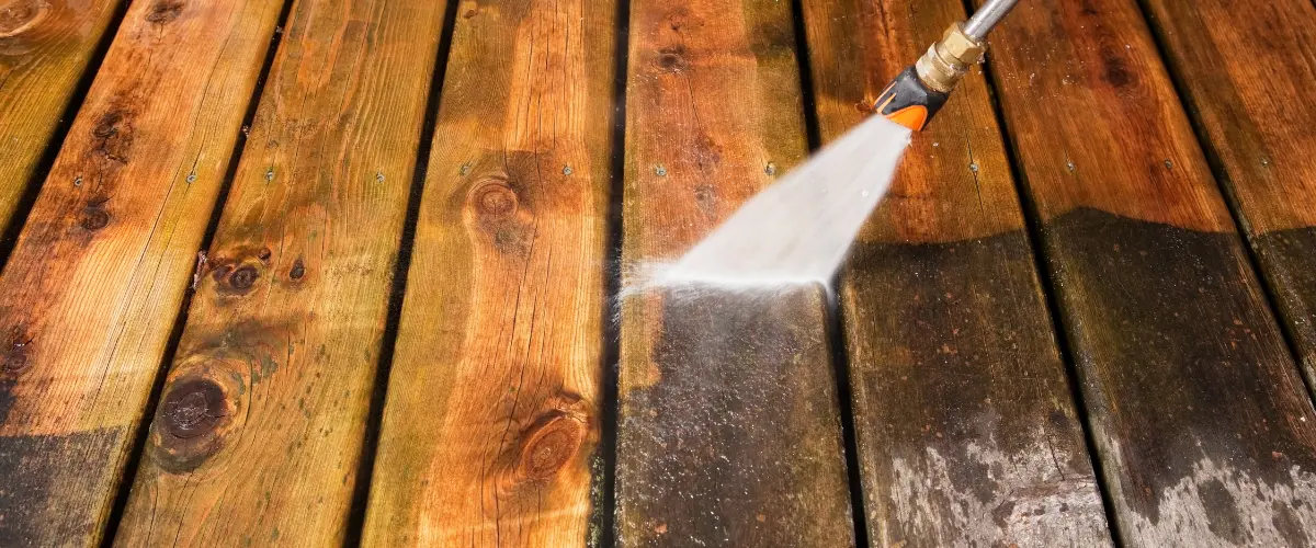 Power washing wooden deck boards to remove grime and restore wood