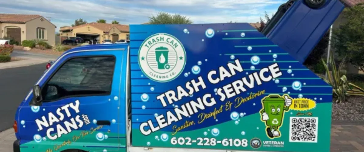 A blue and green Nasty Cans trash can cleaning service truck parked on a street in a residential area.