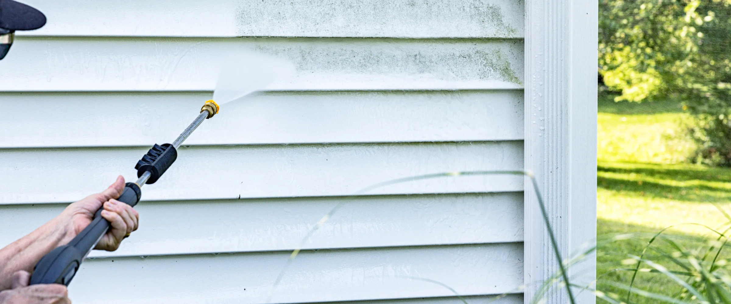 A person uses a pressure washer to clean dirty white house siding, removing grime with a powerful spray. A person uses a pressure washer to clean dirty white house siding, removing grime with a powerful spray.