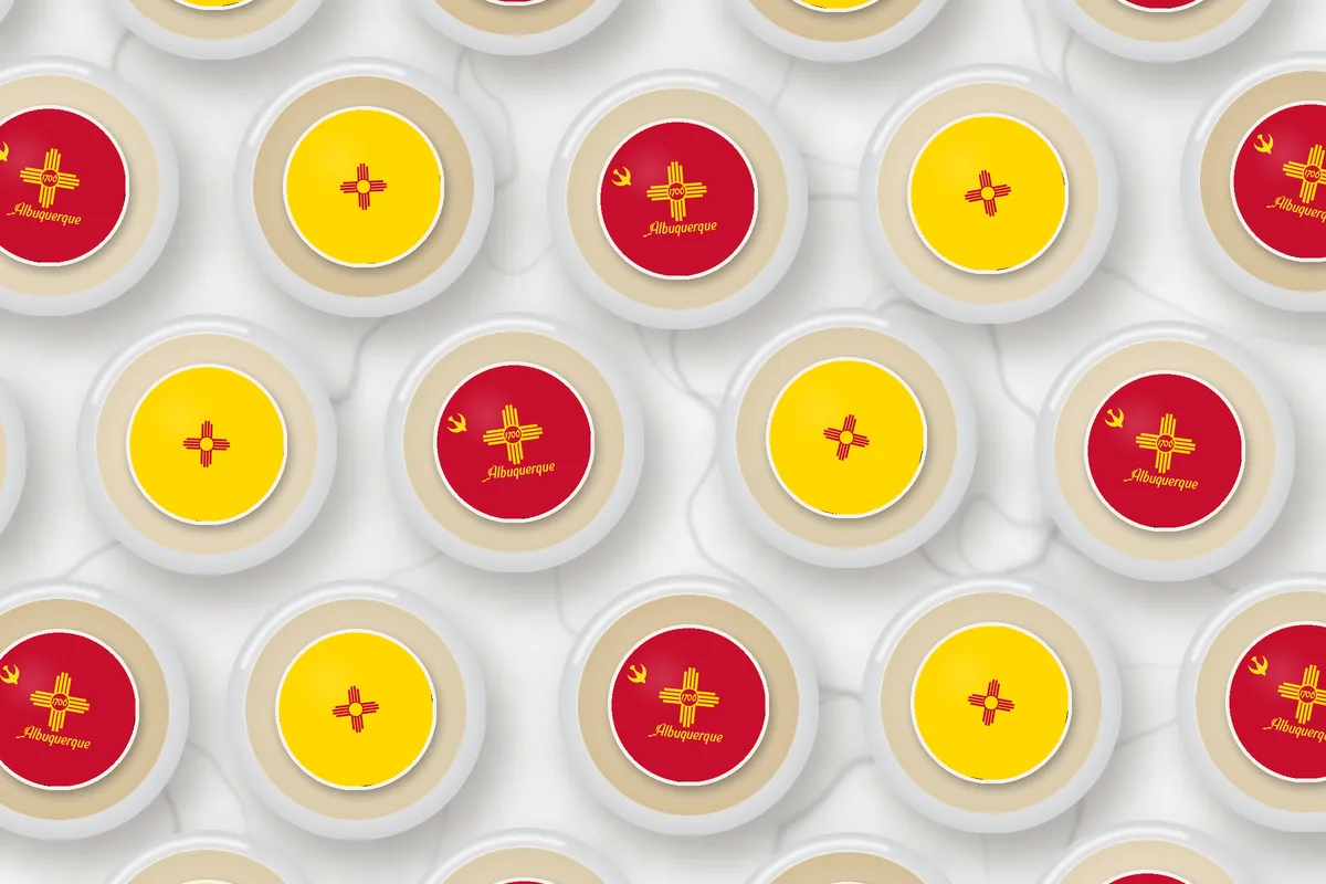 Cocktails topped with edible drink toppers printed with the Albuquerque city flag and the New Mexico flag