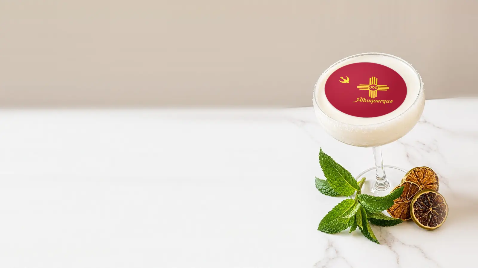 Coupe cocktail topped with a round edible frosting sheet topper printed with the Albuquerque city flag