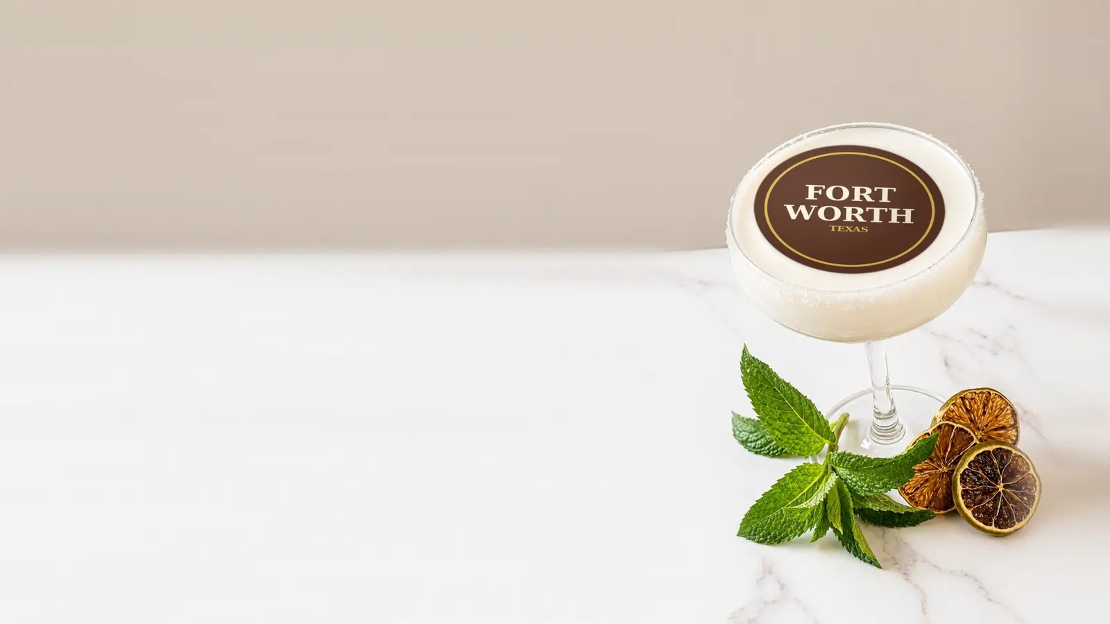 Coupe cocktail topped with a round edible frosting sheet topper printed with the name Fort Worth, Texas, in a gold ring