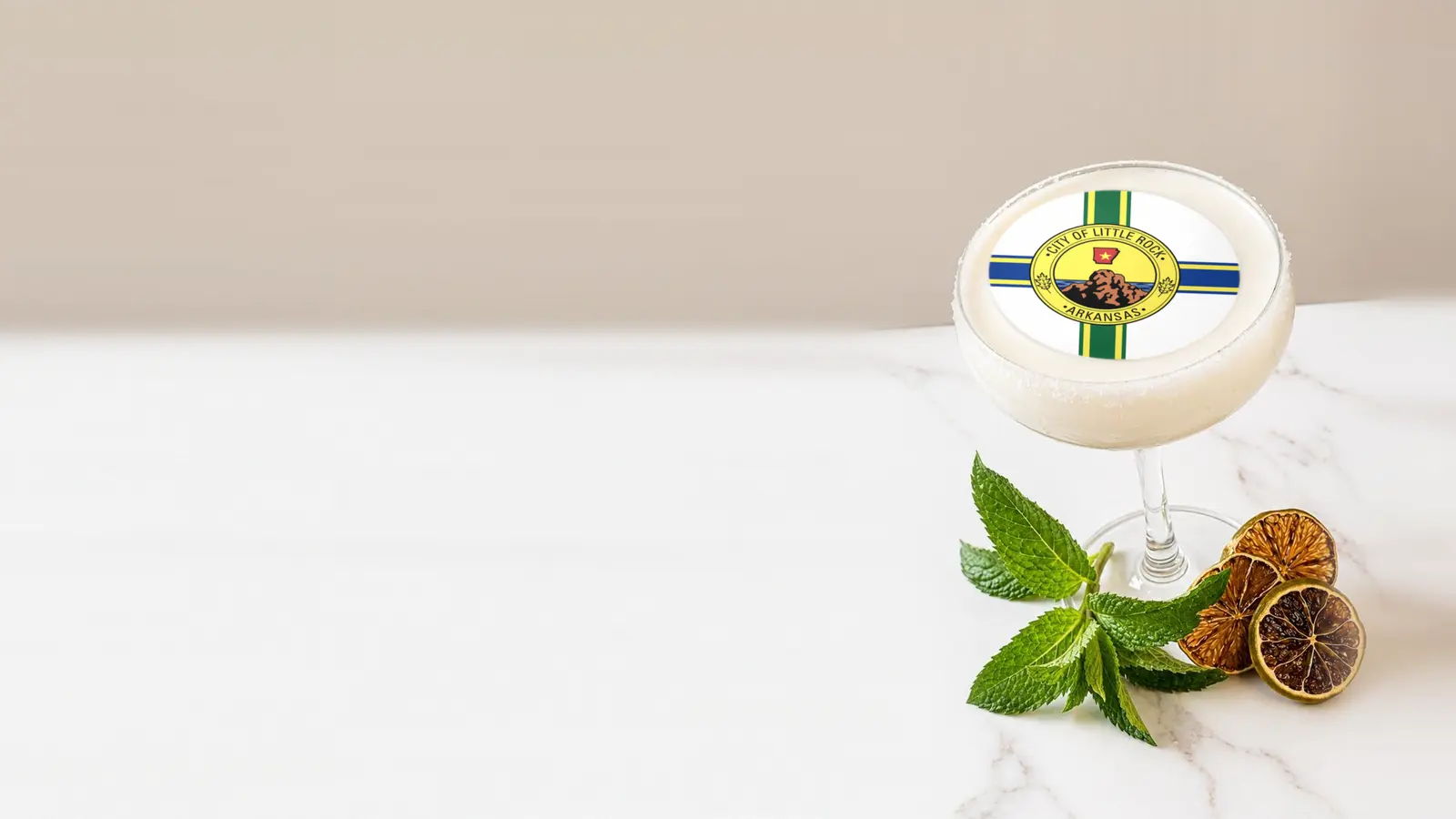 Coupe cocktail topped with a round edible frosting sheet topper printed with the Little Rock city flag