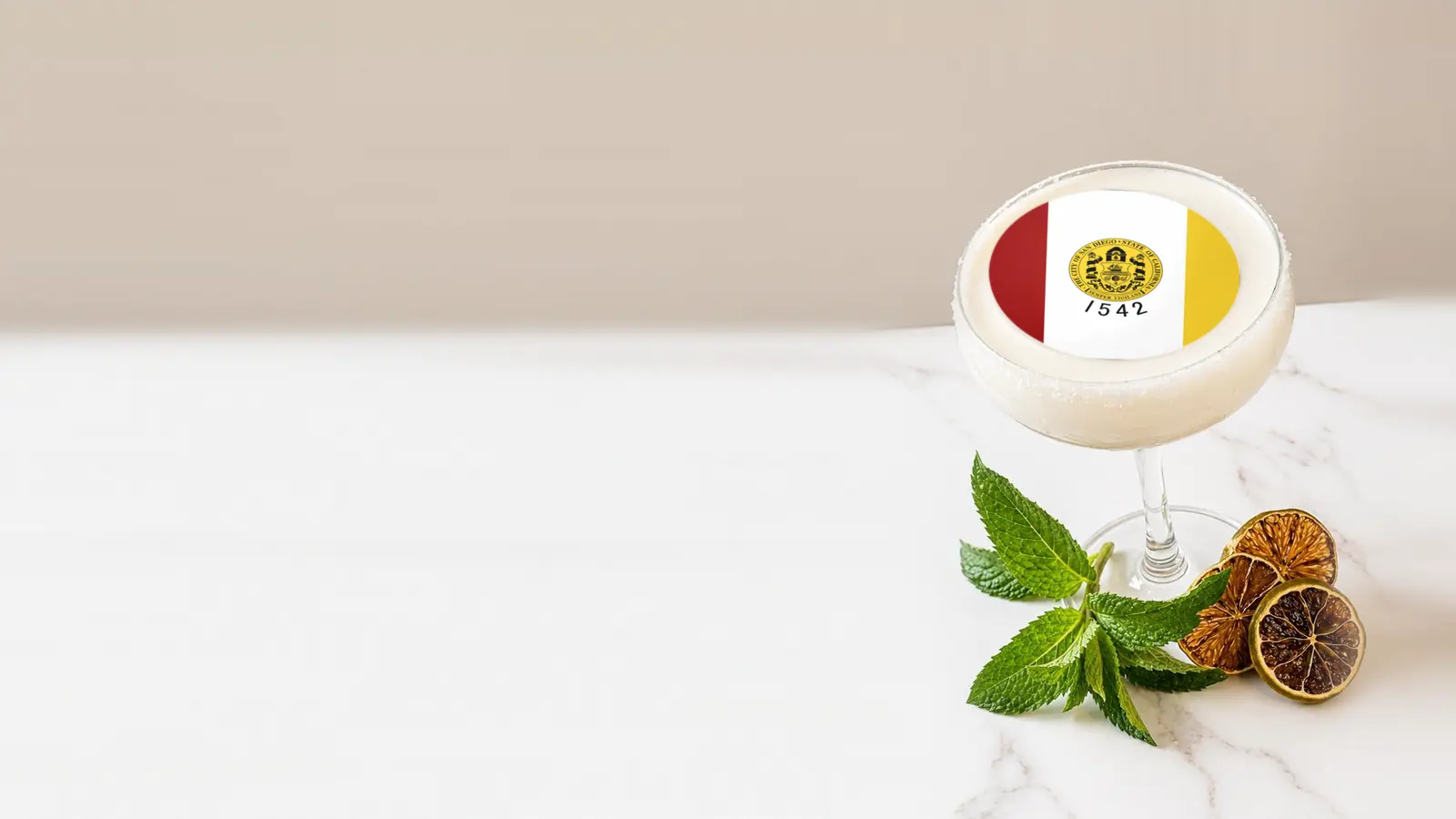 Coupe cocktail topped with a round edible frosting sheet topper printed with the San Diego city flag