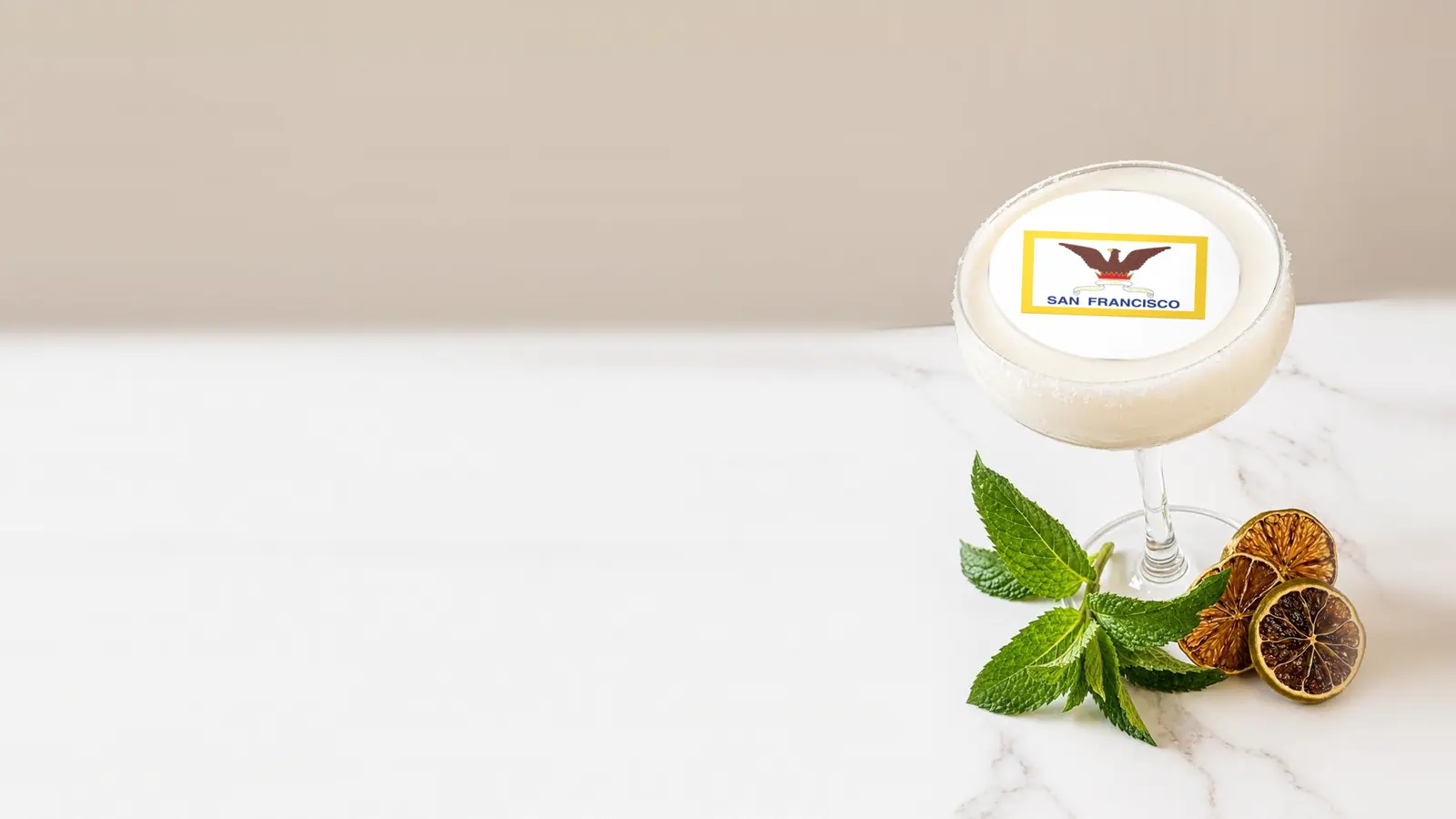 Coupe cocktail topped with a round edible frosting sheet topper printed with the San Francisco city flag