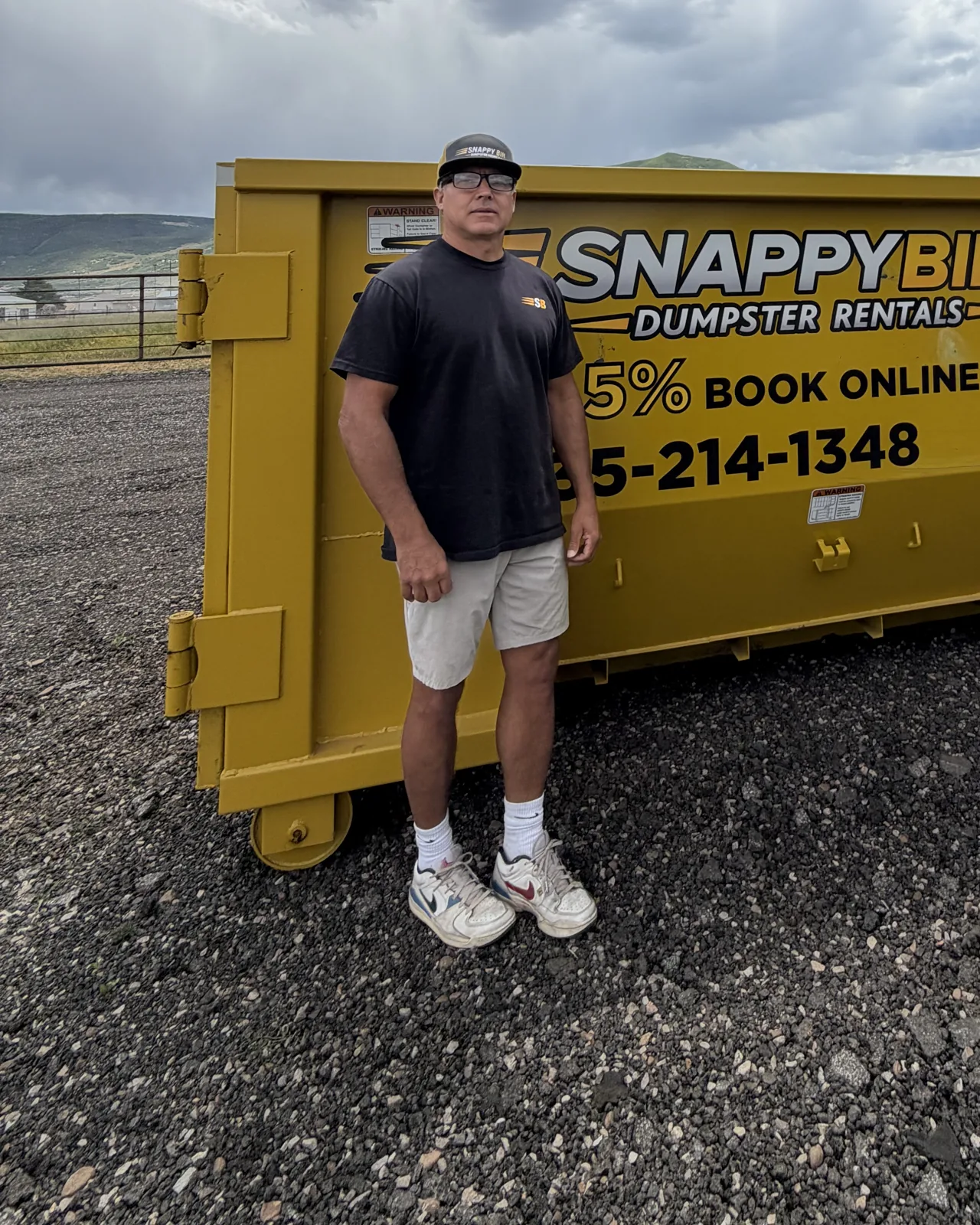 Mike Vleck, founder and owner of Snappy Bin Dumpster Rentals, beside a yellow roll-off dumpster in Park City, UT