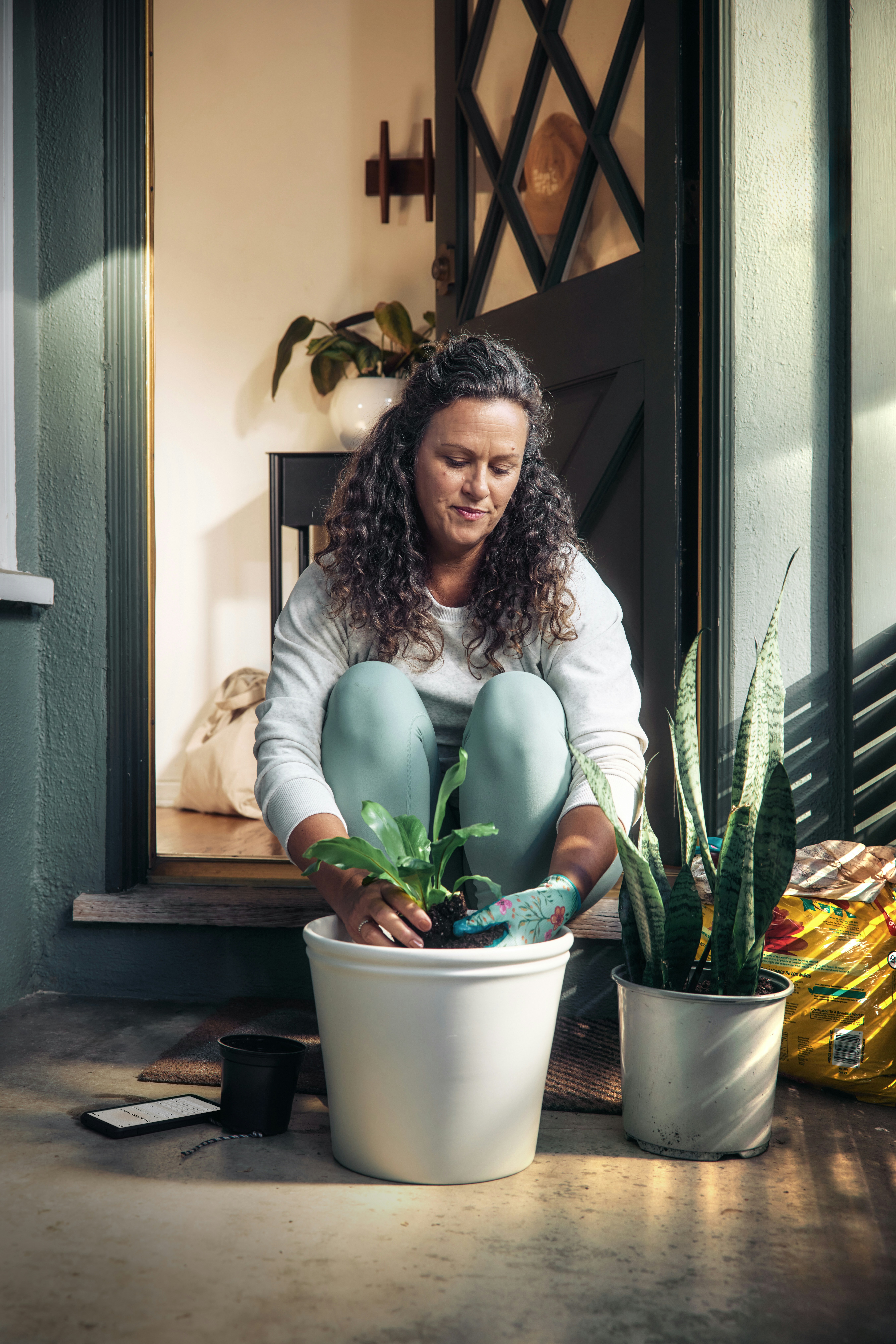 A female is planting a plan in a pot at her door step A female is planting a plan in a pot at her door step