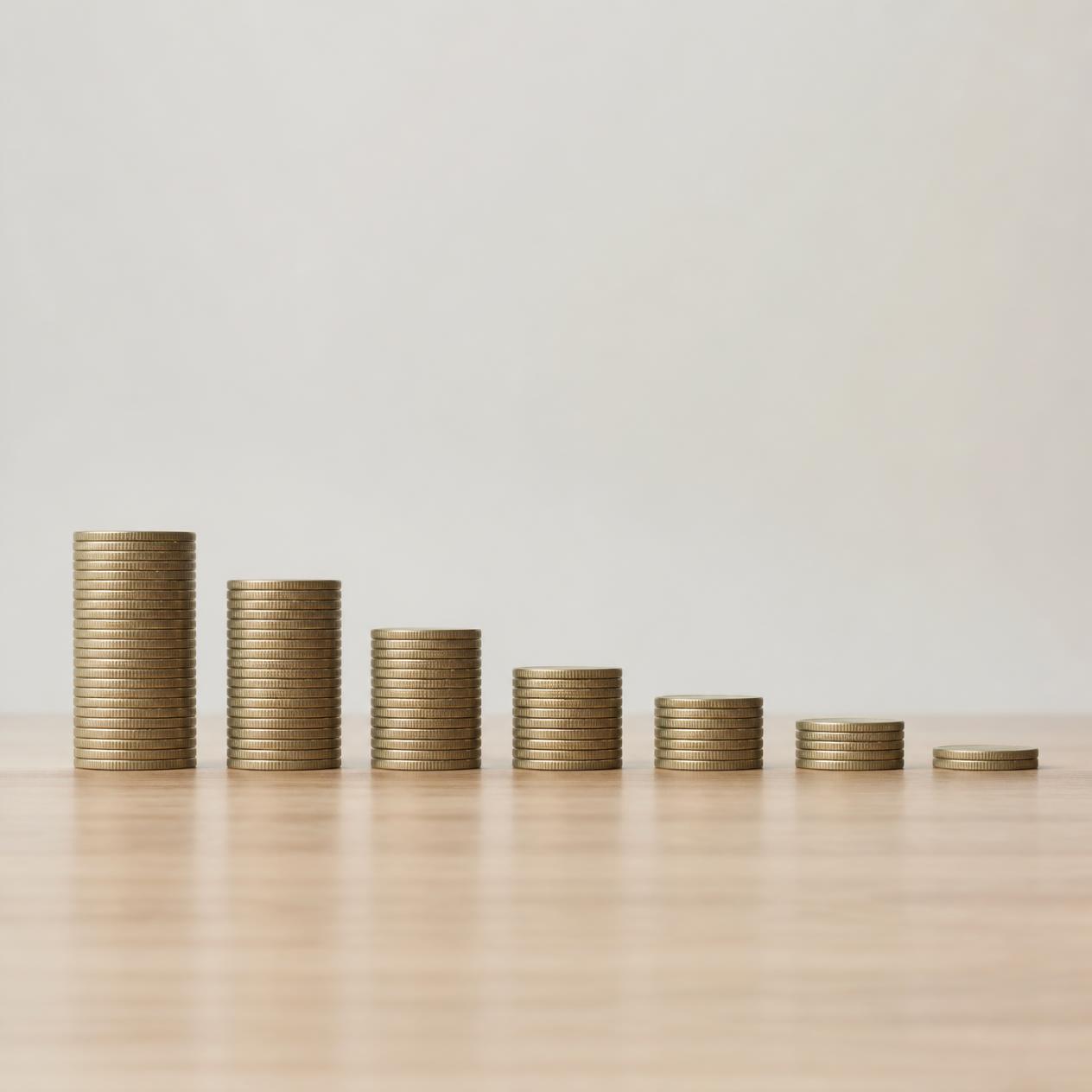 A neat row of small stacked coins or blocks decreasing in size from left to right, soft natural lighting, clean minimalist composition, photorealistic, conveys steady progress, no text, top-down or side angle A neat row of small stacked coins or blocks decreasing in size from left to right, soft natural lighting, clean minimalist composition, photorealistic, conveys steady progress, no text, top-down or side angle