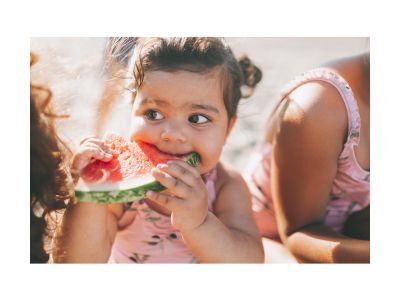Niña sonriendo mientras come una rebanada de sandía