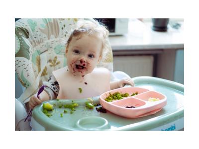 Bebé aprendiendo a comer en una silla alta