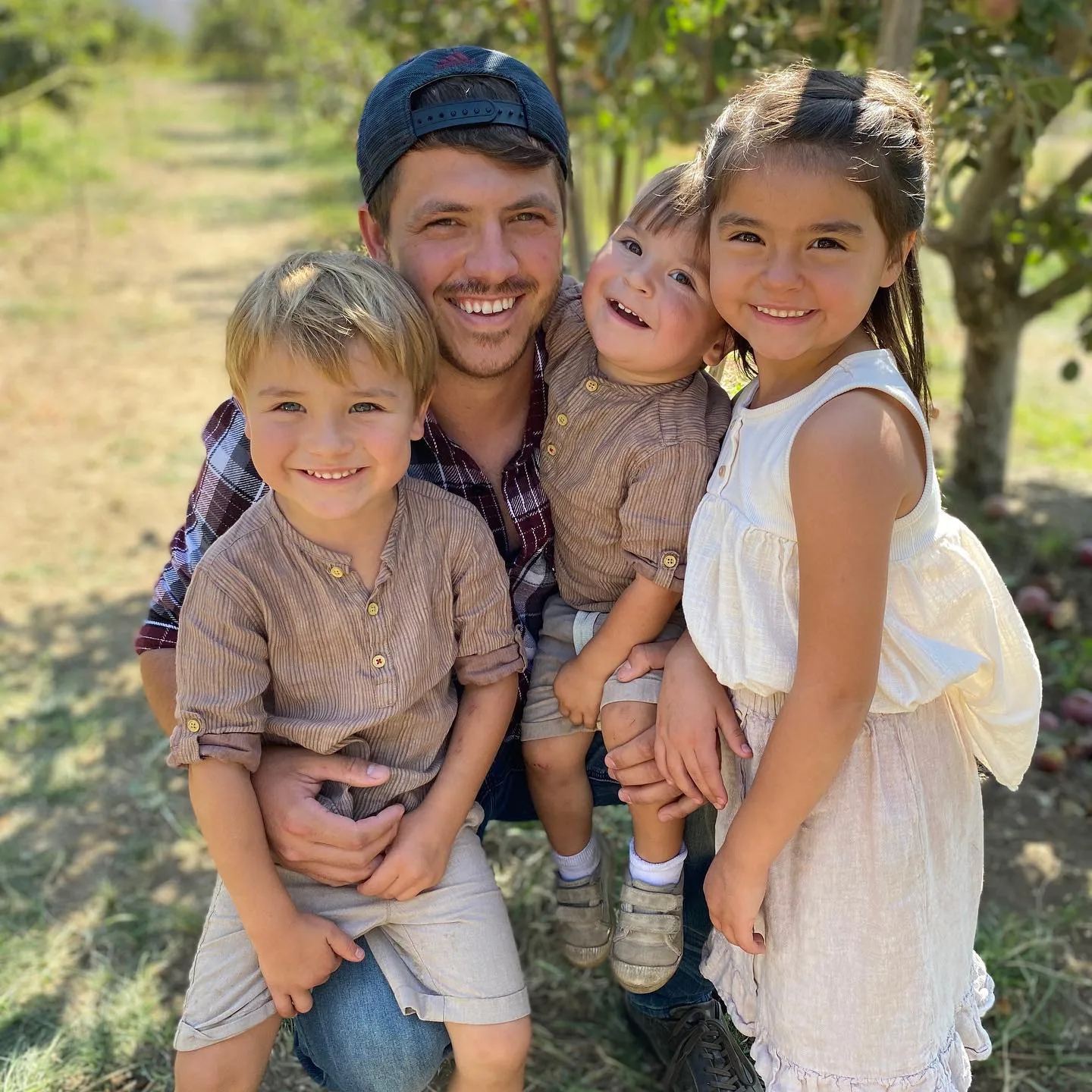 Tanner and three of his smiling children enjoying an apple orchard outing