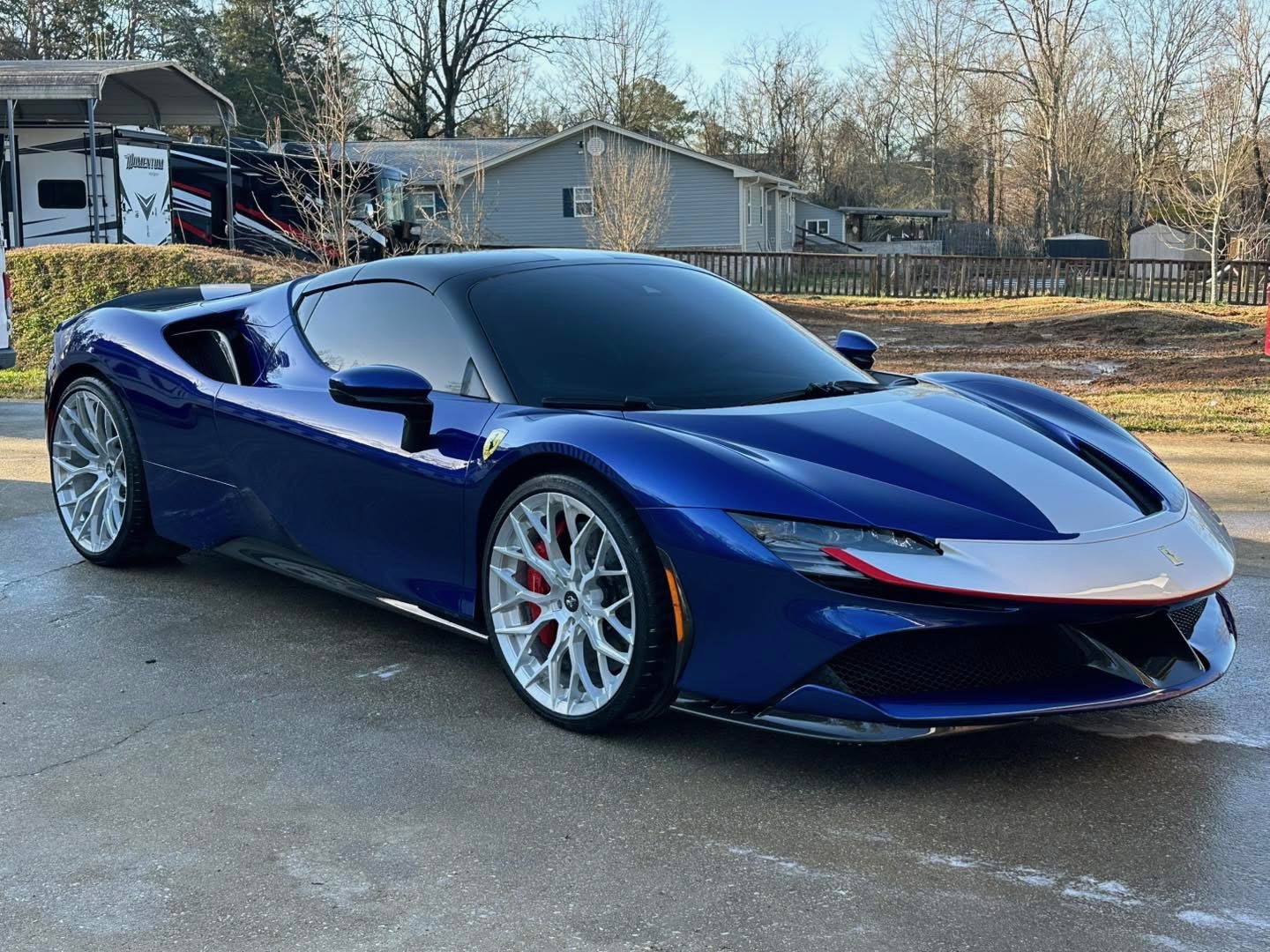 Blue Ferrari SF90 Spider with silver racing livery, silver wheels, and red brake calipers