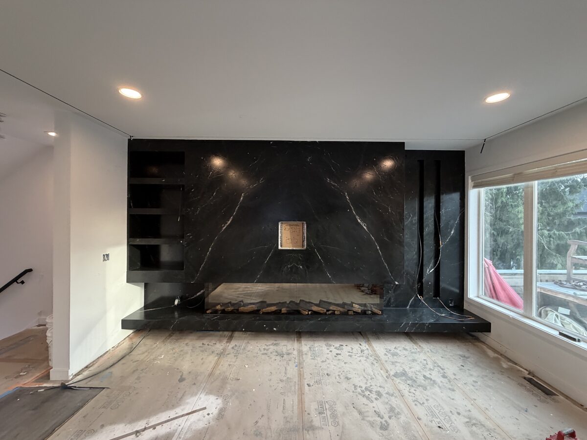 Floor-to-ceiling black soapstone fireplace surround with built-in shelving