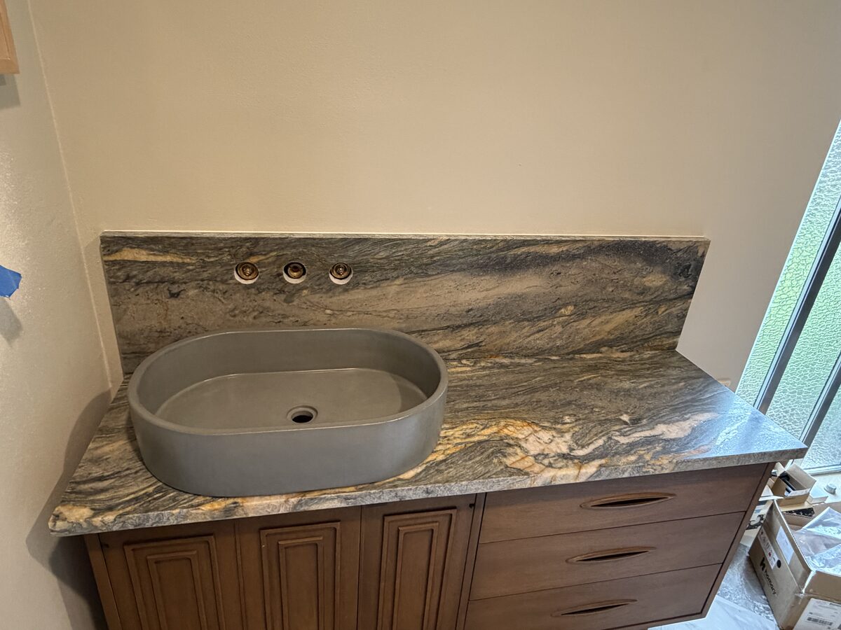 Custom bathroom vanity with dramatic veined stone and concrete vessel sink