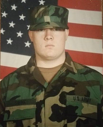 Jeremy in U.S. Army uniform in front of the American flag.