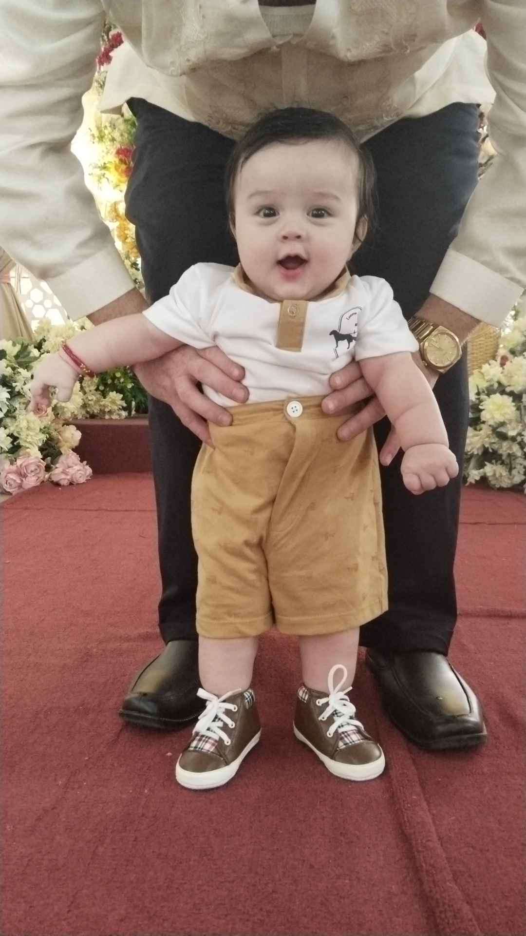 Baby George dressed for the wedding, supported by Jeremy.