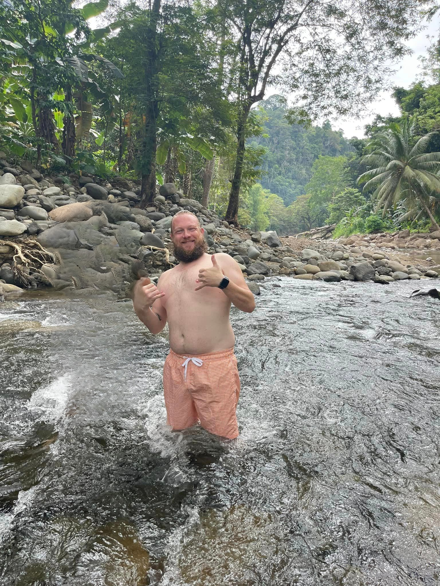 Jeremy standing in the river on his first river trip in the Philippines, grinning.
