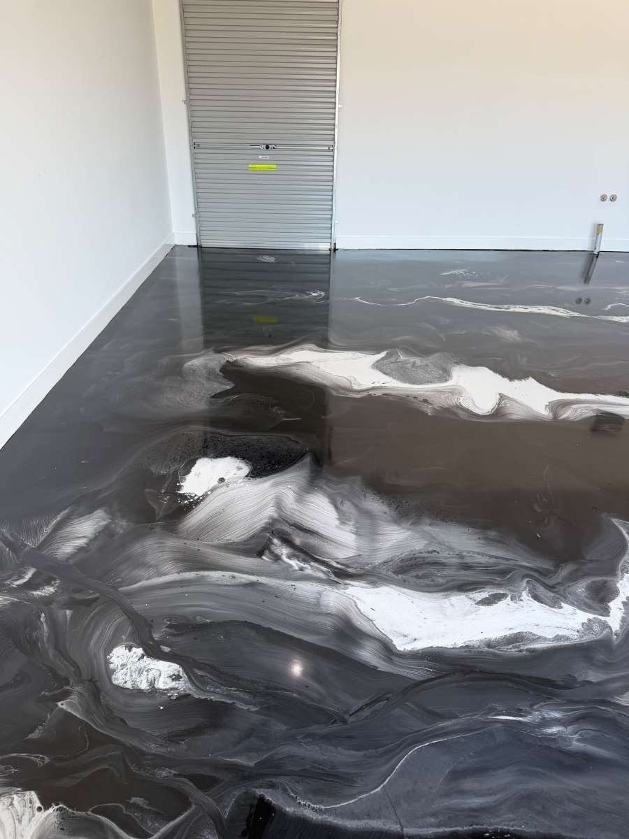 Wide view of the hand-finished metallic epoxy floor catching ambient light across the room