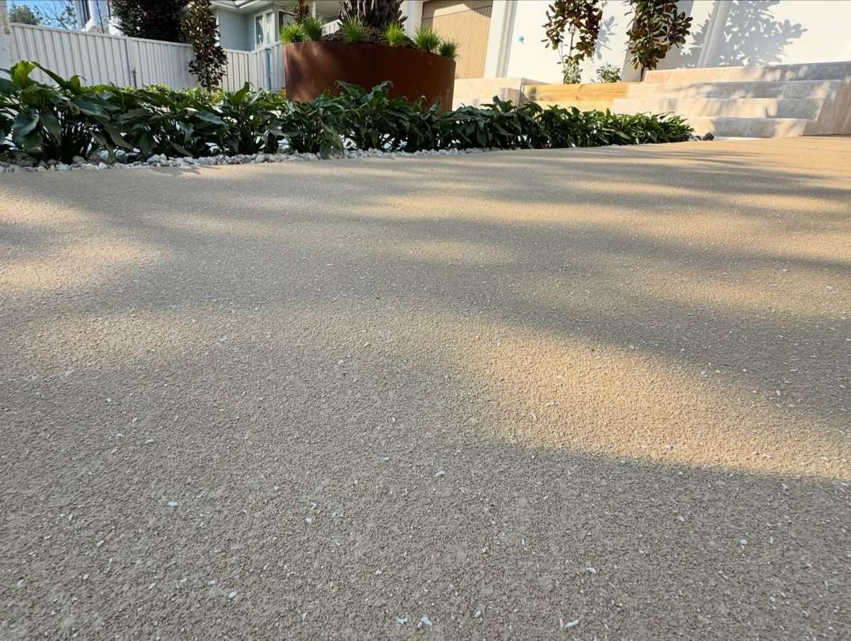 Finished textured Spray Crete resurfaced driveway at a modern Brighton home with garden greenery beyond