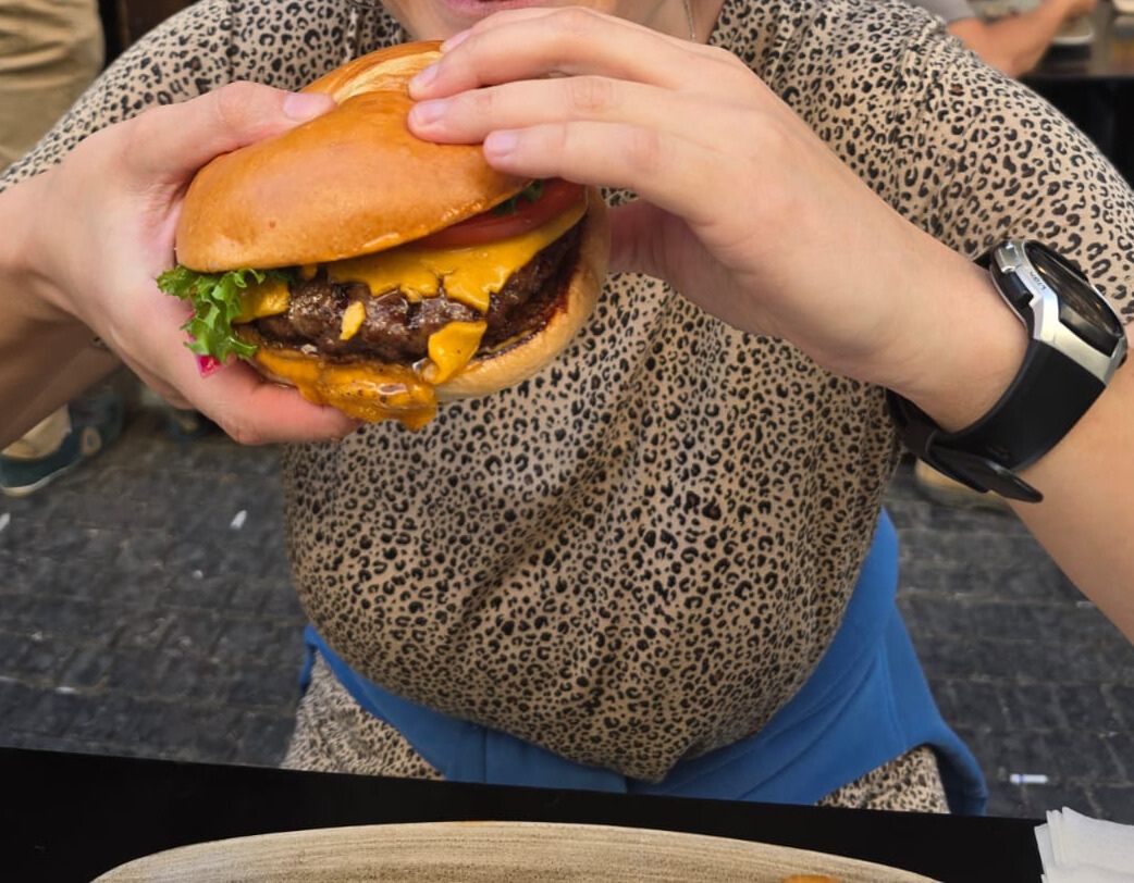 Close-up of a cheeseburger being held at an outdoor restaurant table in Tel Aviv. Close-up of a cheeseburger being held at an outdoor restaurant table in Tel Aviv.