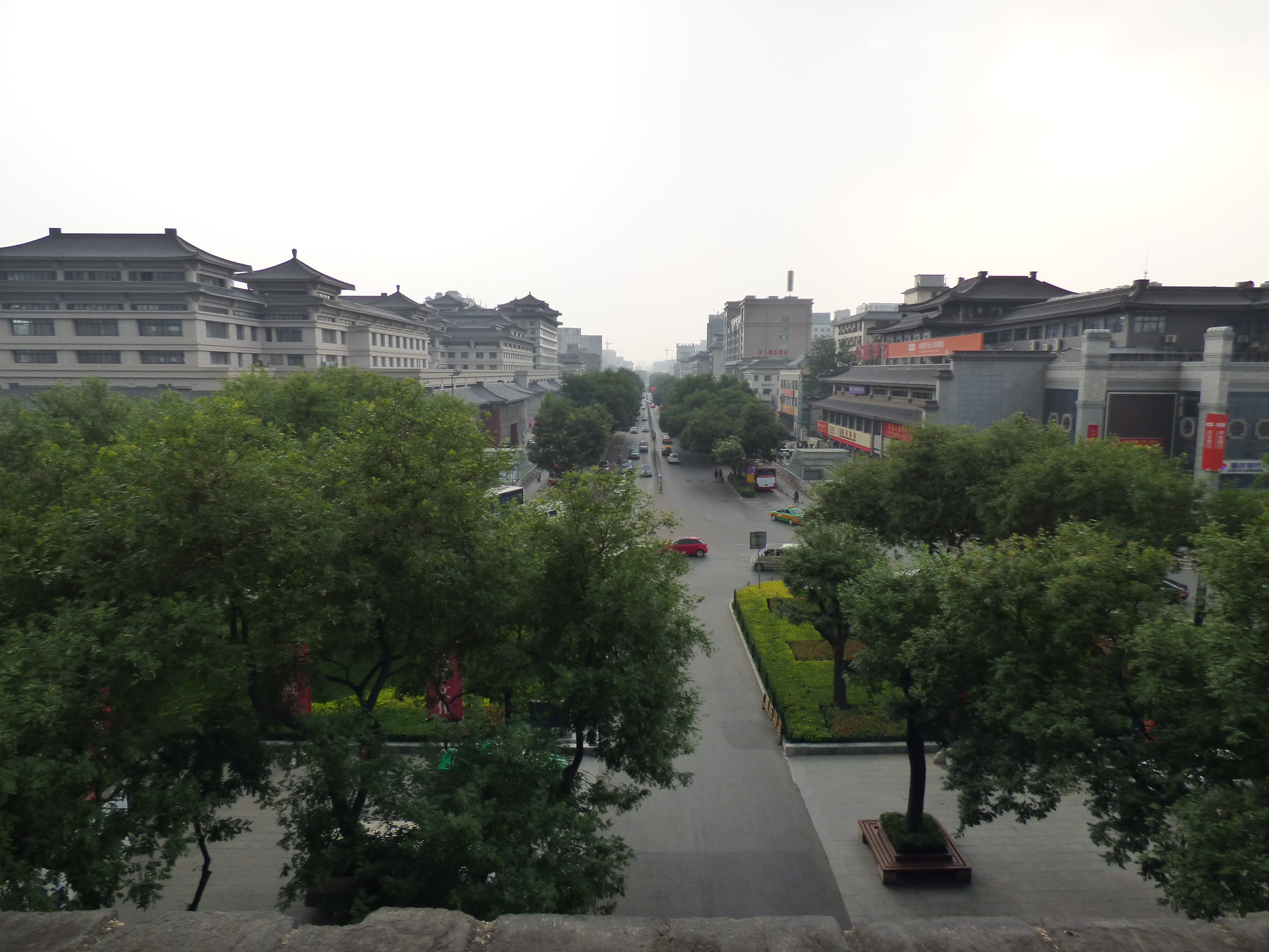 Elevated view from Xi’an’s ancient city wall looking down a tree-lined boulevard with traditional Chinese architecture in Xi’an, China.