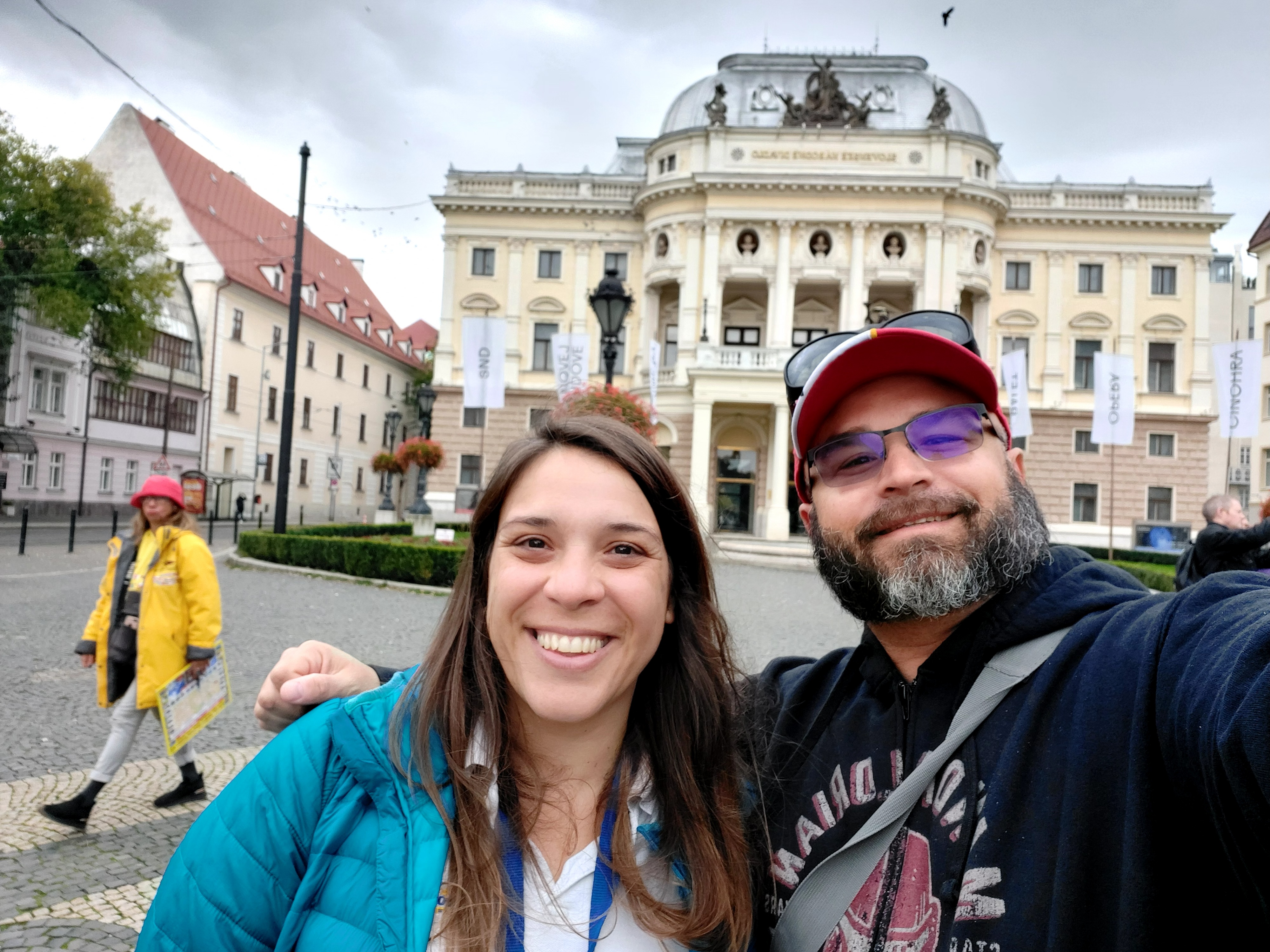 Teacher and local guide standing in front of historic theater in Bratislava, illustrating educational travel and learning through real-world context.