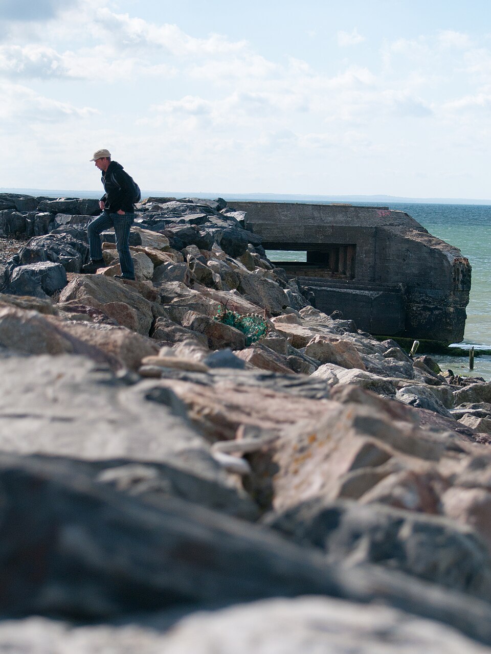 Traveler walking near a preserved German coastal bunker at Grandcamp-Maisy in Normandy, France.
