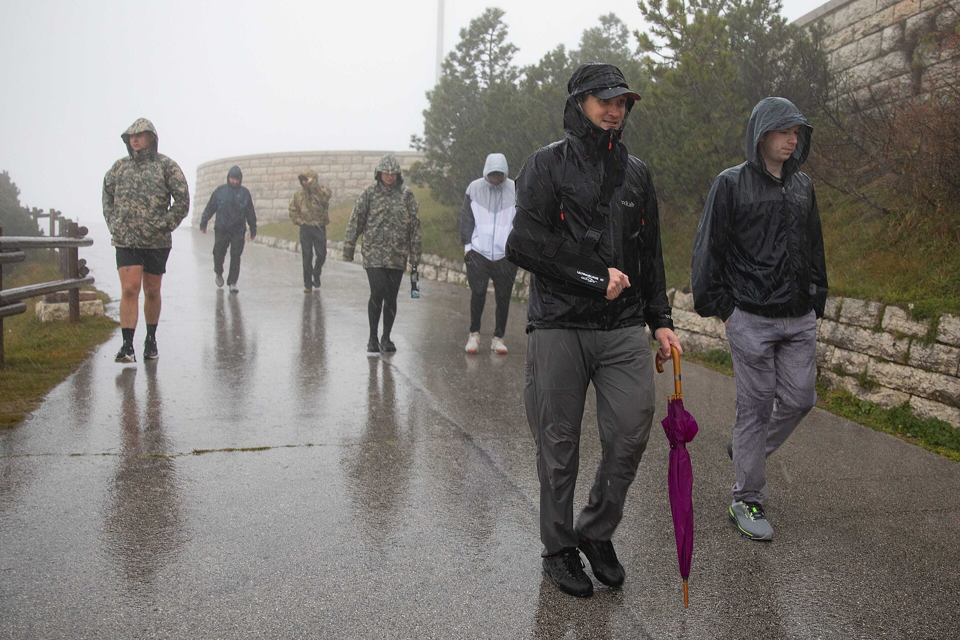 Group of cadets and instructors walking through rainy battlefield terrain at Monte Grappa in Veneto, Italy.