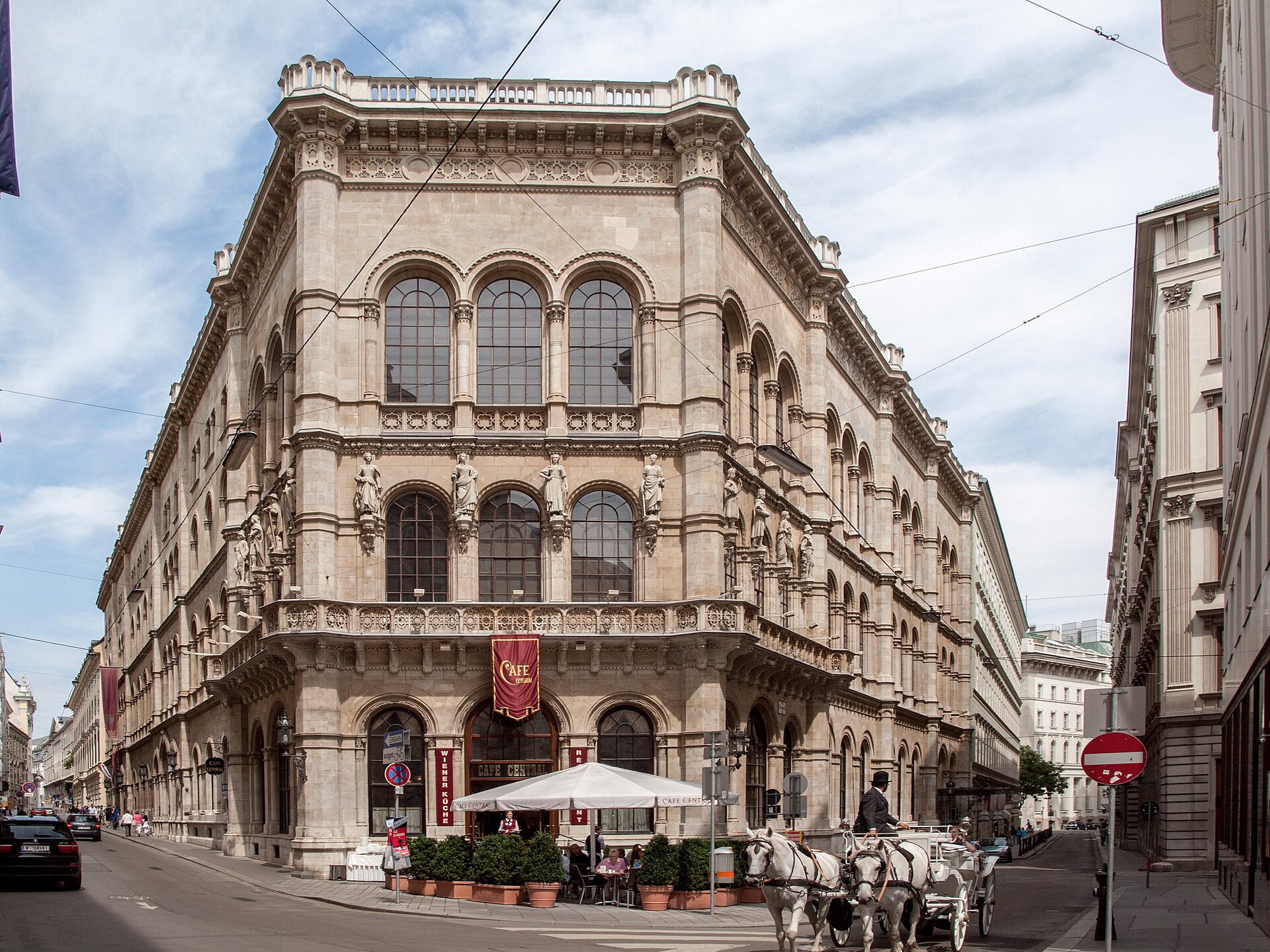 Exterior view of Palais Ferstel in Vienna, featuring historic neo-Renaissance architecture, arched windows, ornate stonework, and the famous Café Central at street level.