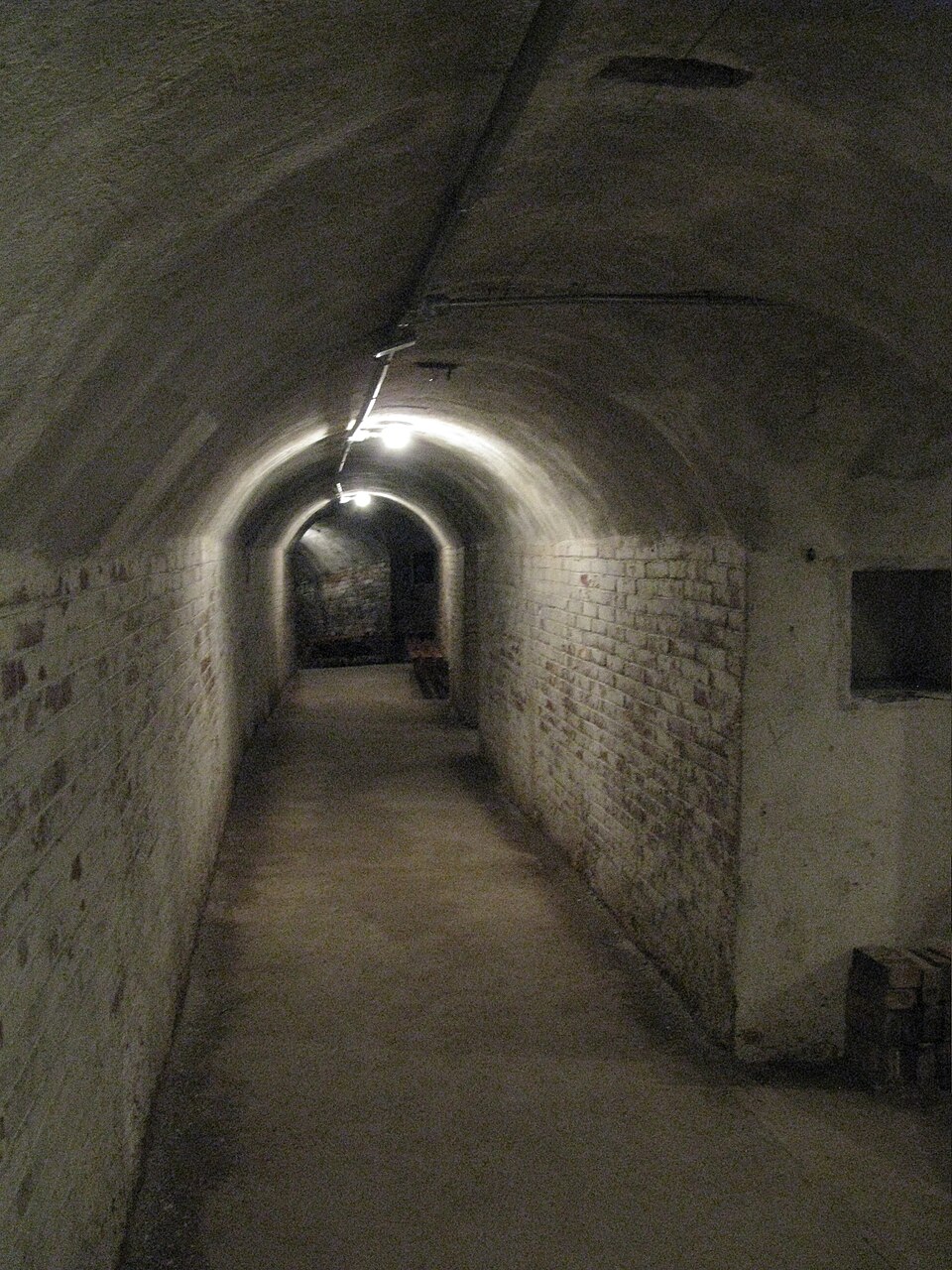 Dimly lit underground corridor inside Refugio 307, showing the preserved brick-lined air raid shelter used by civilians during the Spanish Civil War.