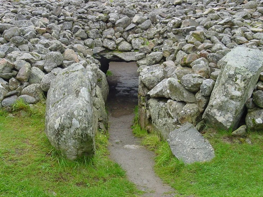 Ancient stone passage entrance surrounded by weathered rocks and grass in Ireland's Brú na Bóinne archaeological landscape. Ancient stone passage entrance surrounded by weathered rocks and grass in Ireland's Brú na Bóinne archaeological landscape.