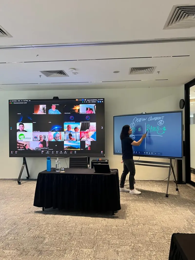 A presenter writing on a MAXHUB display during a hybrid call