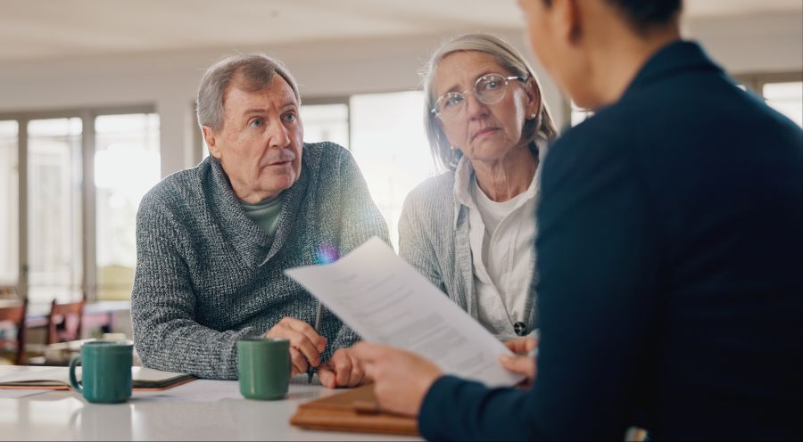 An older couple talking through papers with an adviser