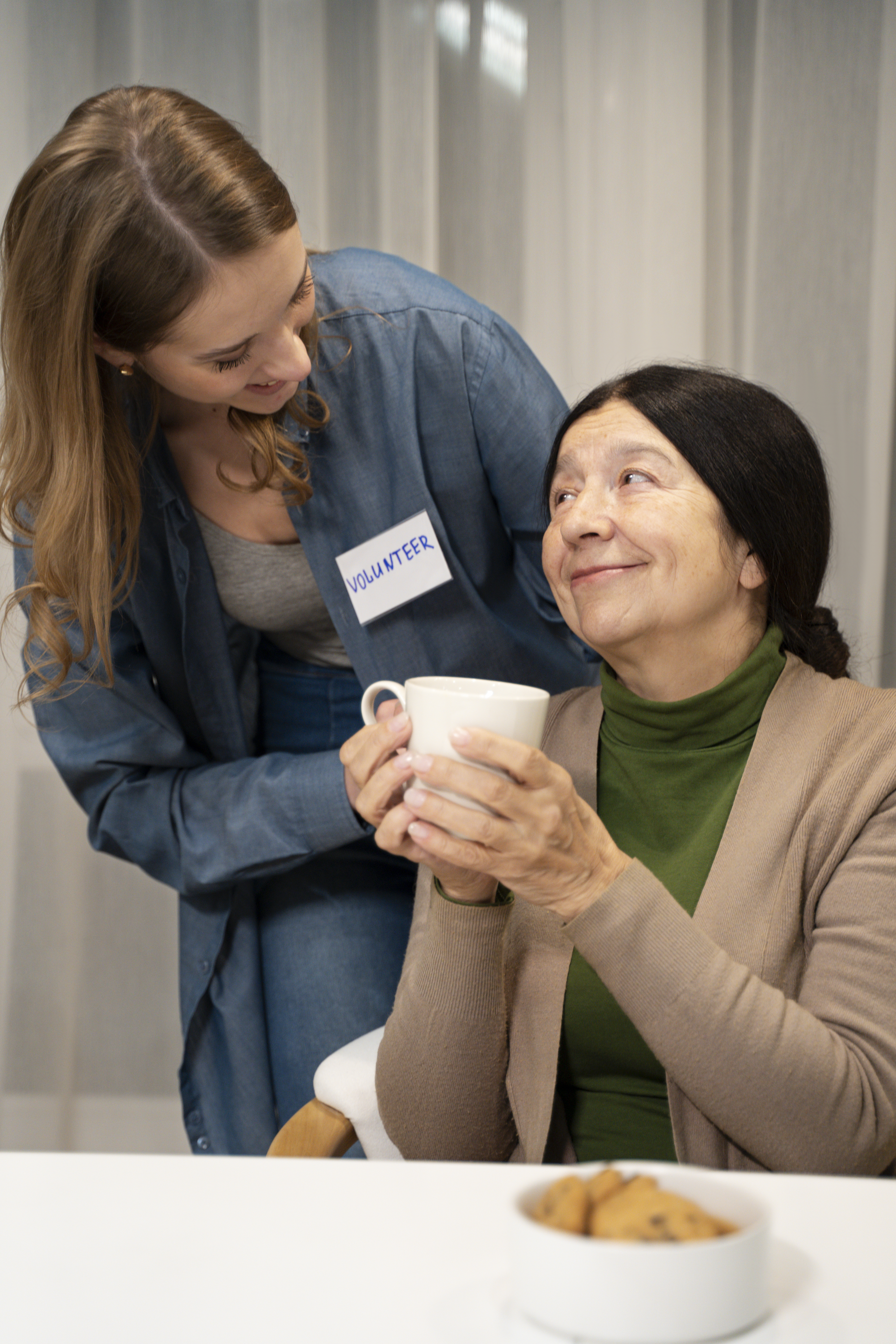 A carer sharing a cup of tea with an older woman