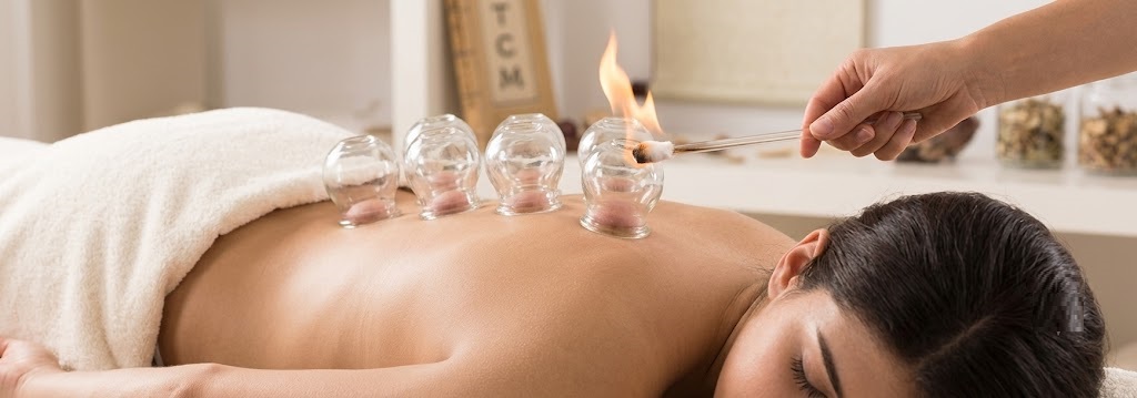 Close-up of a glass cupping vessel creating suction on a client's shoulder during treatment