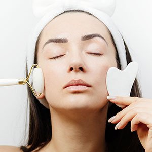 Close-up of a smooth-edged gua sha tool being drawn along the skin during a treatment