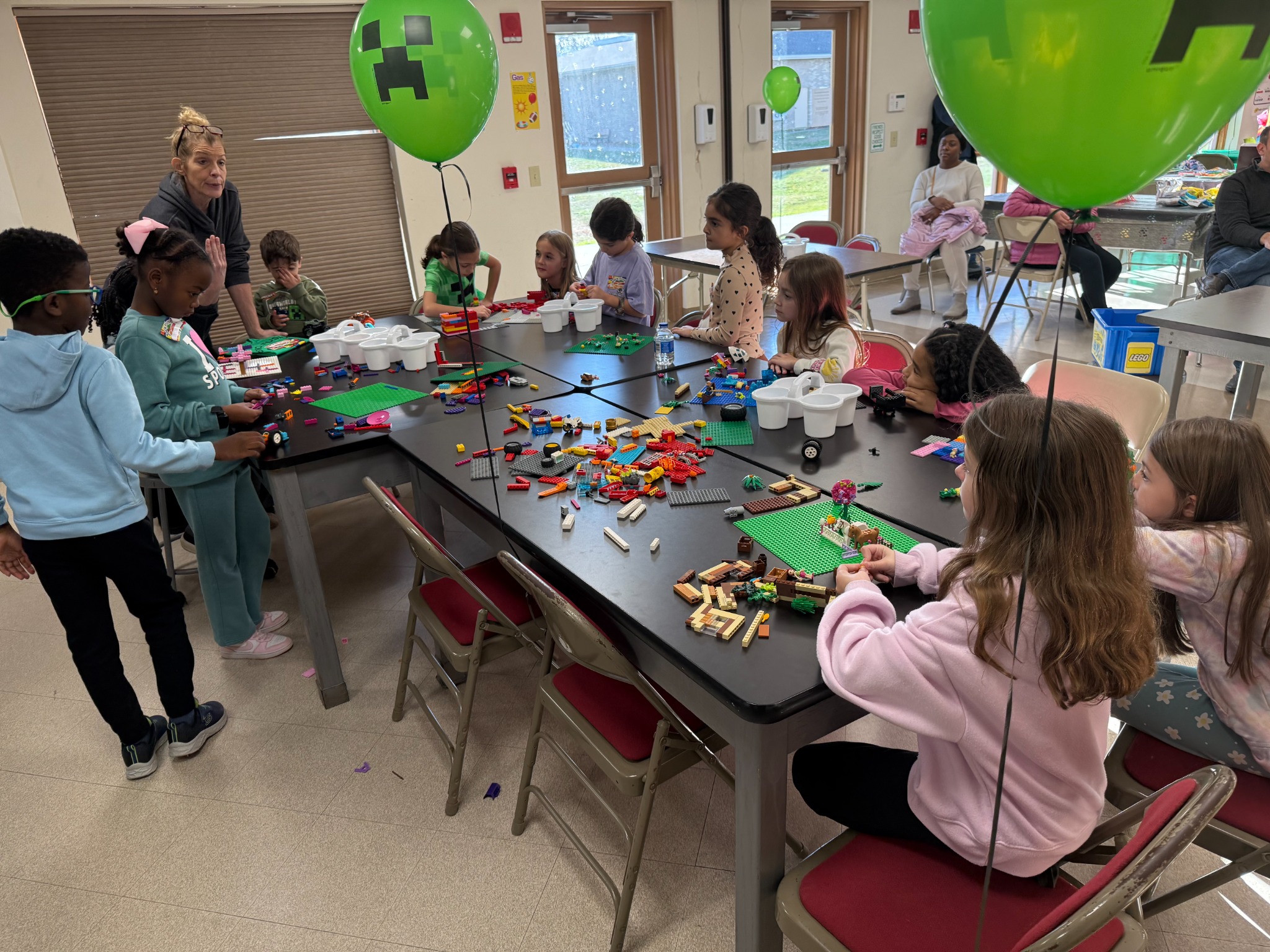 Birthday guests building together at decorated party tables