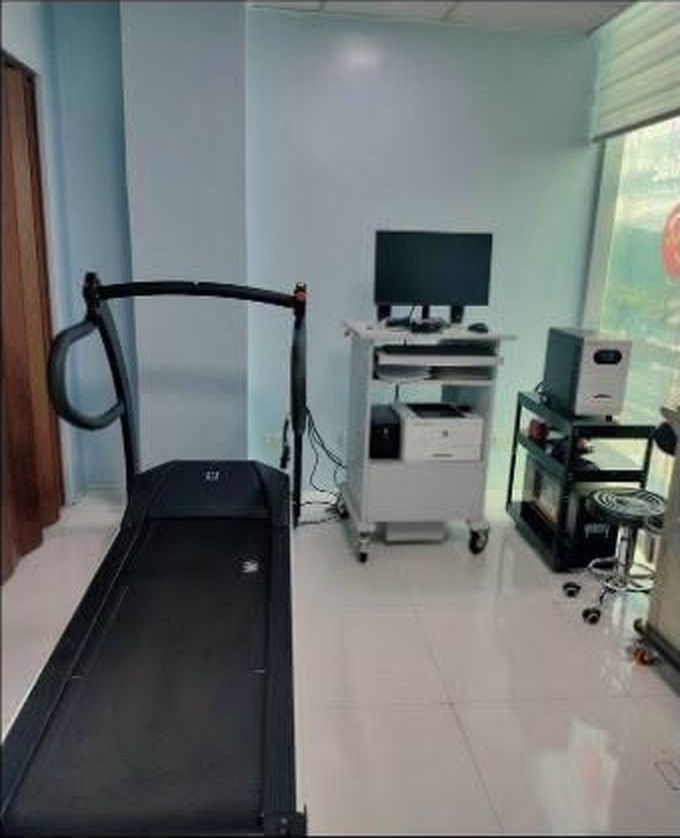 A clinical laboratory room with a stress-test treadmill, monitor cart and printer