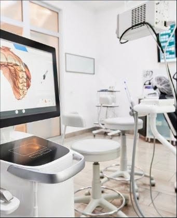 A dental surgery with a scanner display, chair and instrument cart