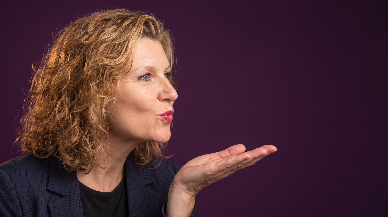 Patricia Heemskerk blaast een kushandje, op een aubergine achtergrond